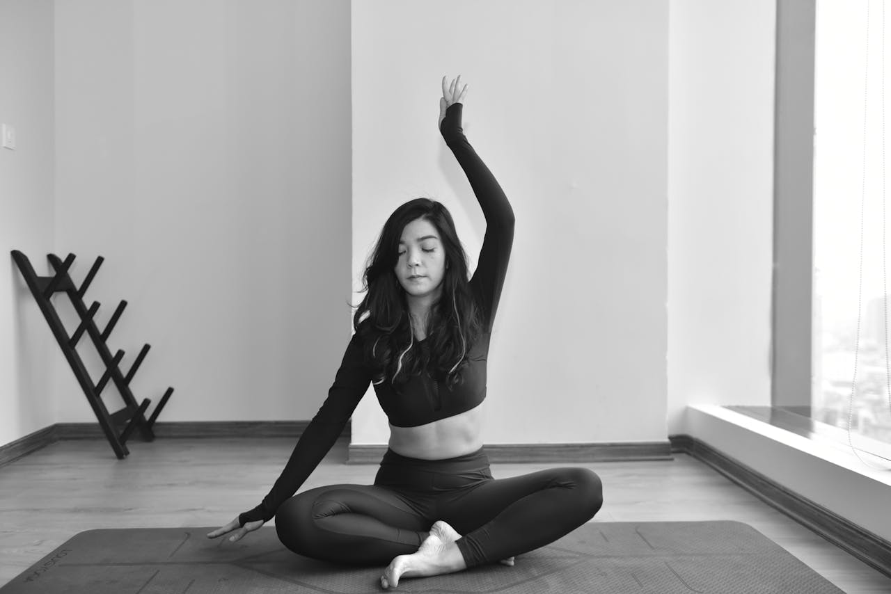 Young woman practicing yoga indoors, focused on relaxation and mindfulness in a serene space.